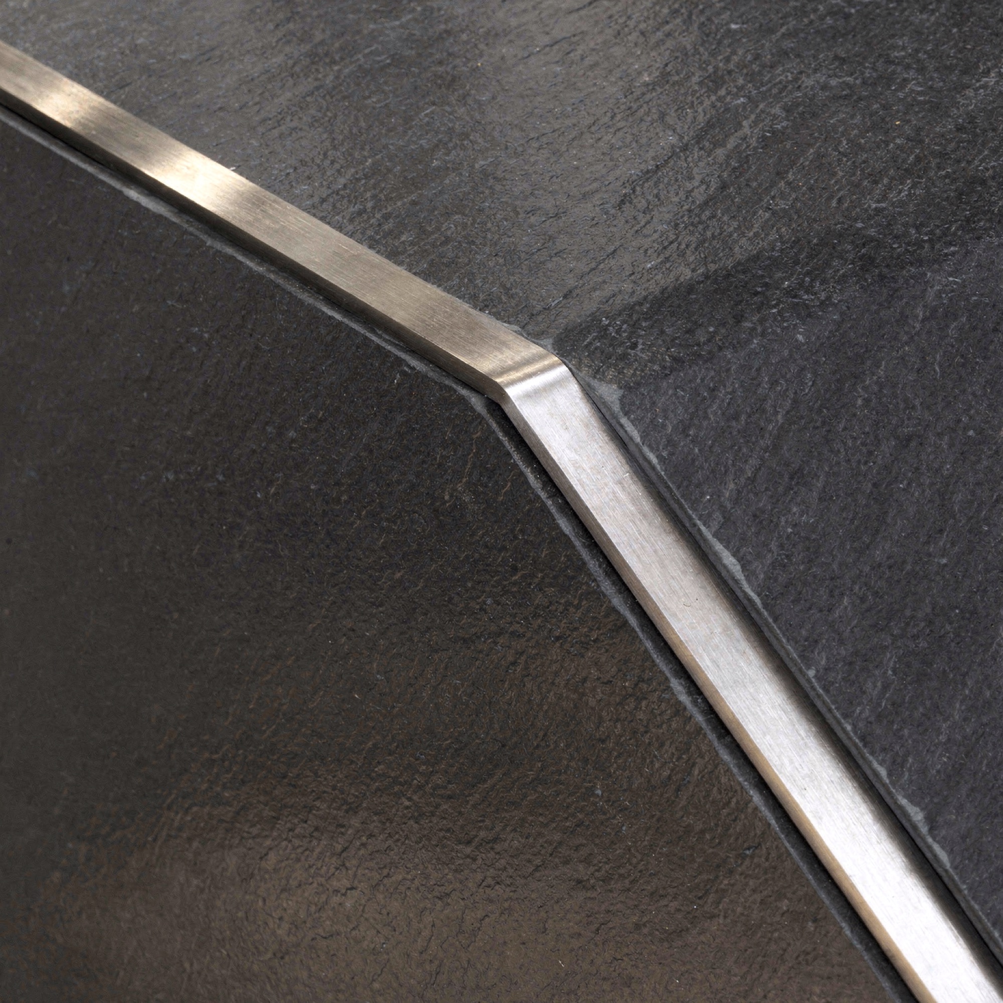 Longform media-wall slate and stainless-steel detail